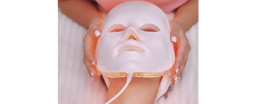 Close-up of a woman wearing an LED red light therapy mask to boost collagen and improve skin texture.